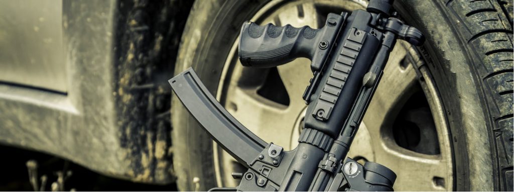 a fully automatic mp5 leaning against a tire
