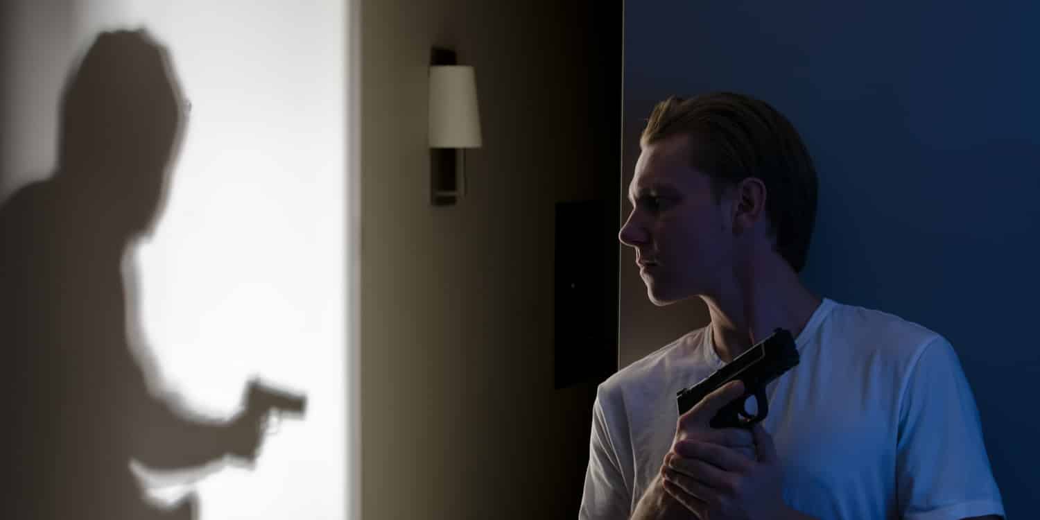 a man holding a handgun to defend himself inside house