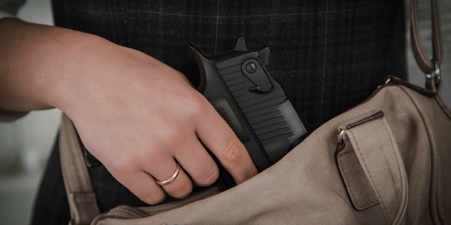 a hand pulling a gun out of a purse representing a concealed carry mindset