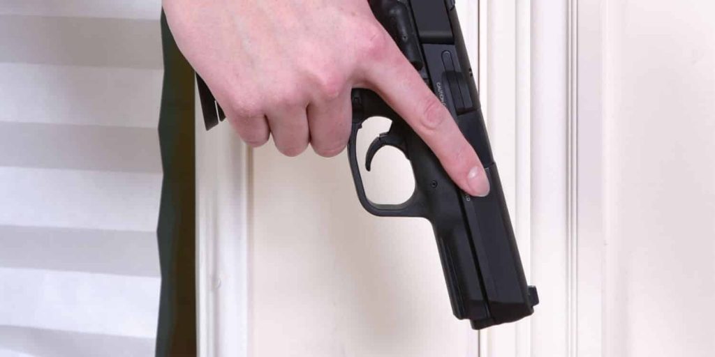 a person holding a gun after staging firearms for home defense
