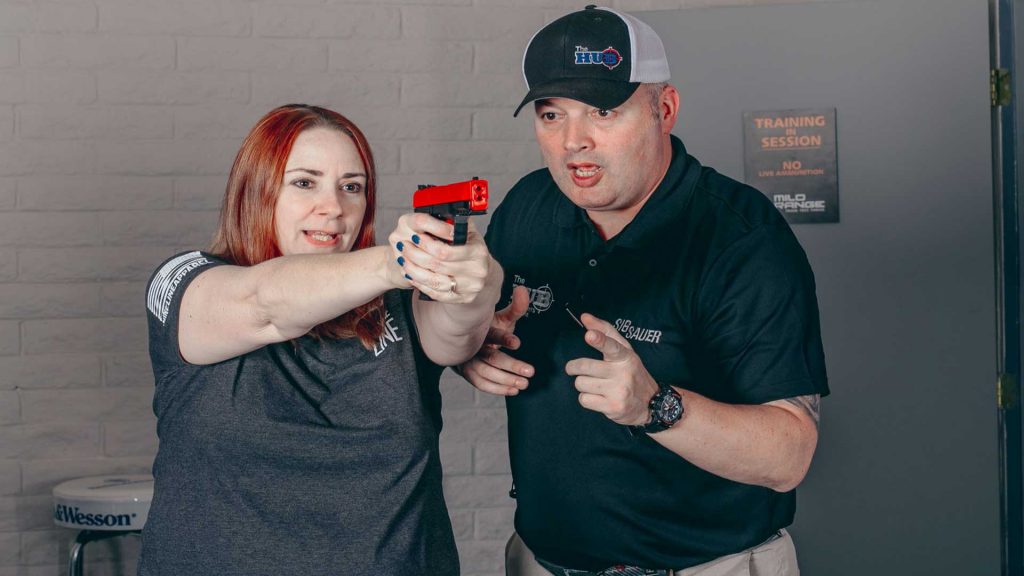the hub instructor teaching a woman how to fire the gun properly